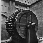 Black and white photograph of a large wooden model of a hydraulic ventilator