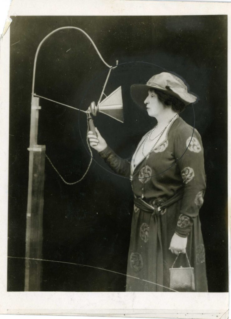 Black and white photograph of Dame Ellie Melba singing into an early microphone from 1920