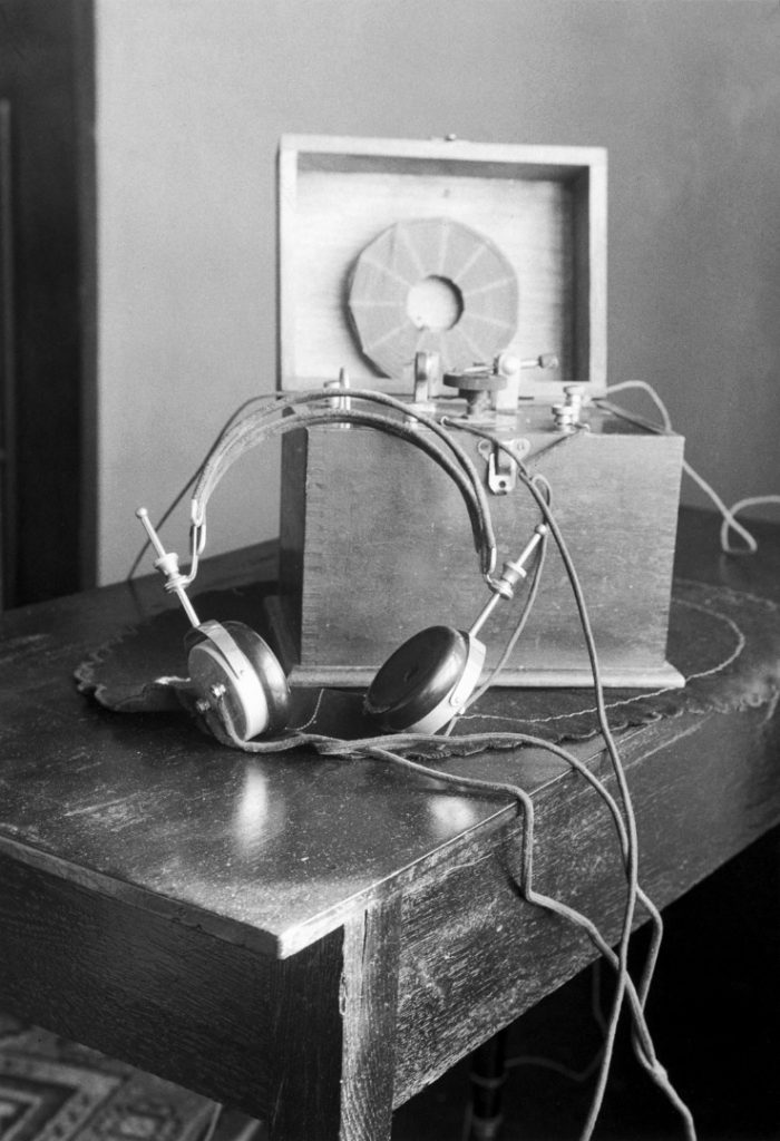 Black and white photograph of an early audio listening device with attached headphones