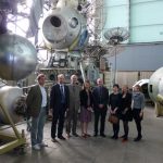 Colour photograph of the Science Museum delegation inside a storage warehouse for old soviet space exploration technology