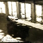 Black and white photograph of a model boat travelling at speed in a water tank testing facility