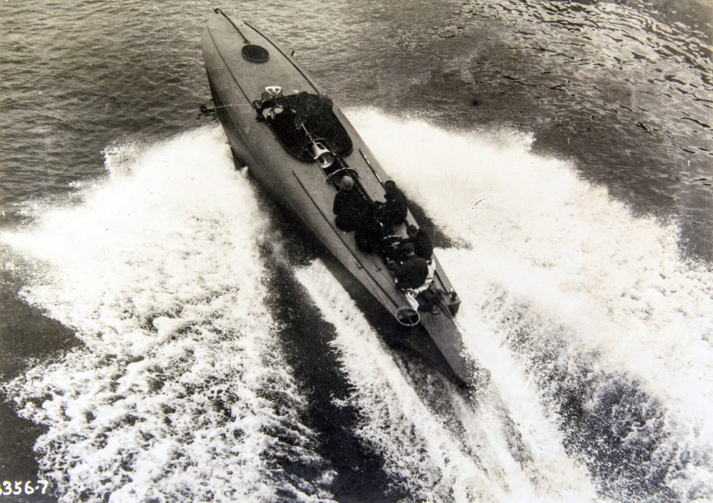 Black and white photograph of a coastal motor boat travelling at speed