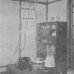 Black and white photograph of a Japanese living room with electricity cables connecting from the light fitting to various electrical devices
