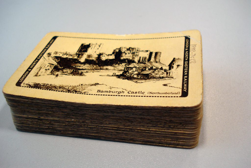 Colour photograph of a pack of playing cards that display a picture of Bamburgh Castle on the underside