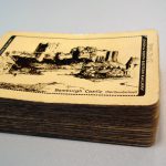 Colour photograph of a pack of playing cards that display a picture of Bamburgh Castle on the underside