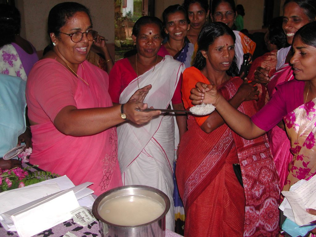 Colour photograph of an indian woman offering cooked rice to others