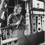 Black and white photograph of a woman working on the construction of an aircraft