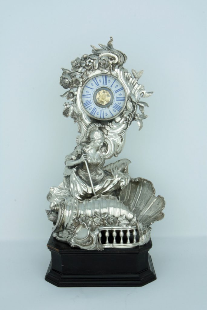 A photograph taken from the front showing the ornate silver clock