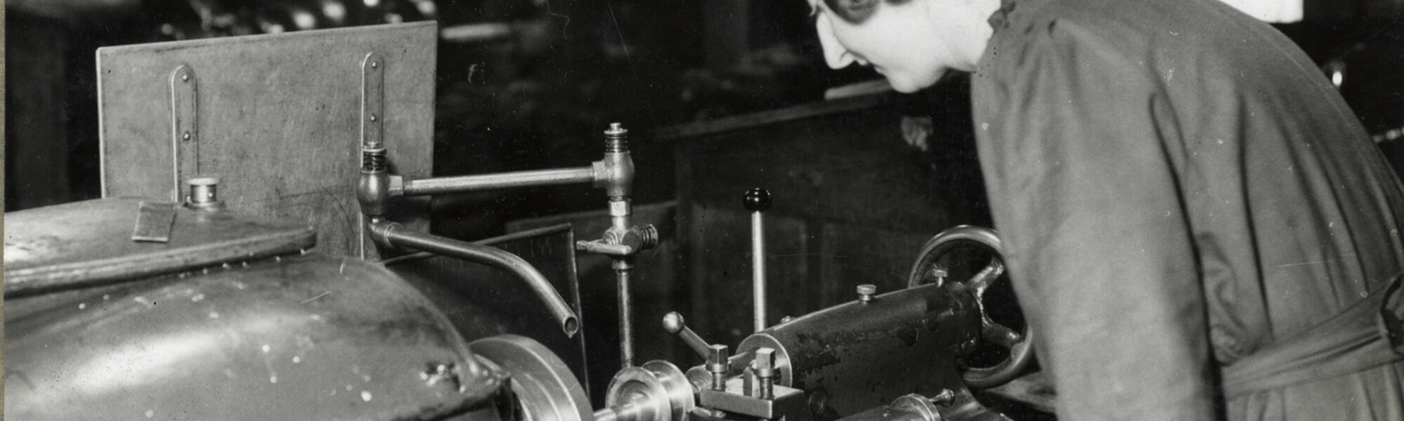 Black and white photograph of a woman working a machine tool during the mid twentieth century