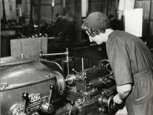 Black and white photograph of a woman working a machine tool during the mid twentieth century