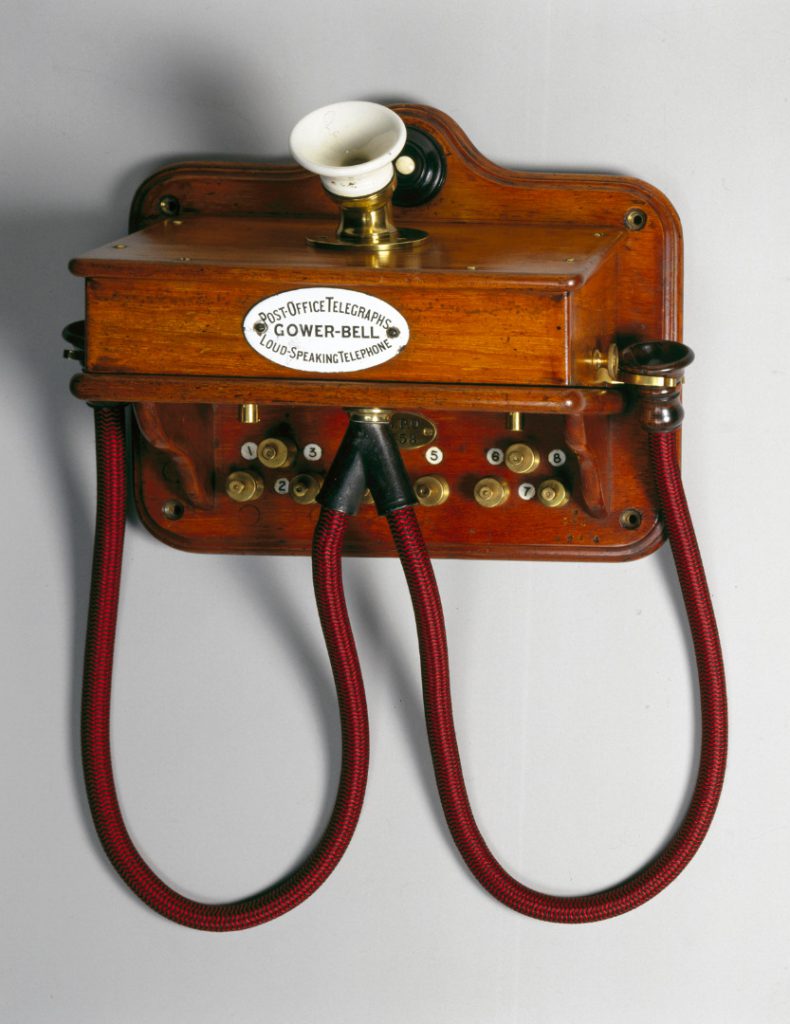 Colour photograph of a wall mounted wooden telephone with two earpieces from the 1880s