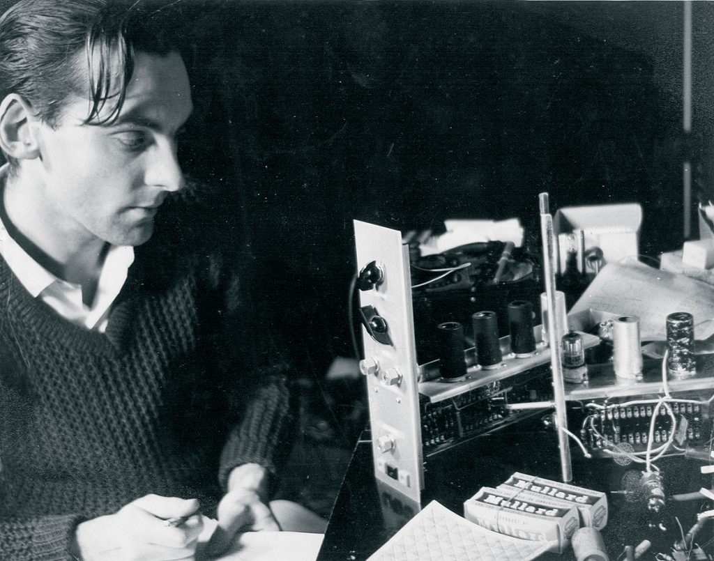Black and white photograph of engineer Graham Wrench writing notes as he works on constructing part of the Oramics Machine