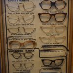 Colour photograph of a 1970s display case showing various styles of NHS spectacles