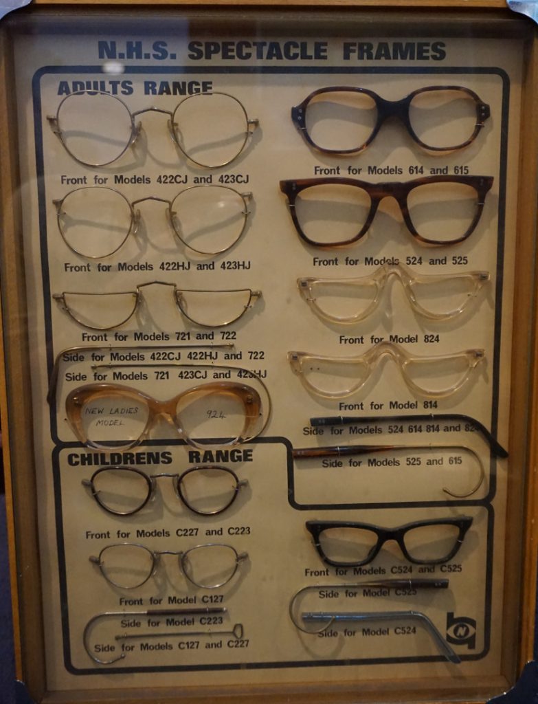 Colour photograph of a 1970s display case showing various styles of NHS spectacles