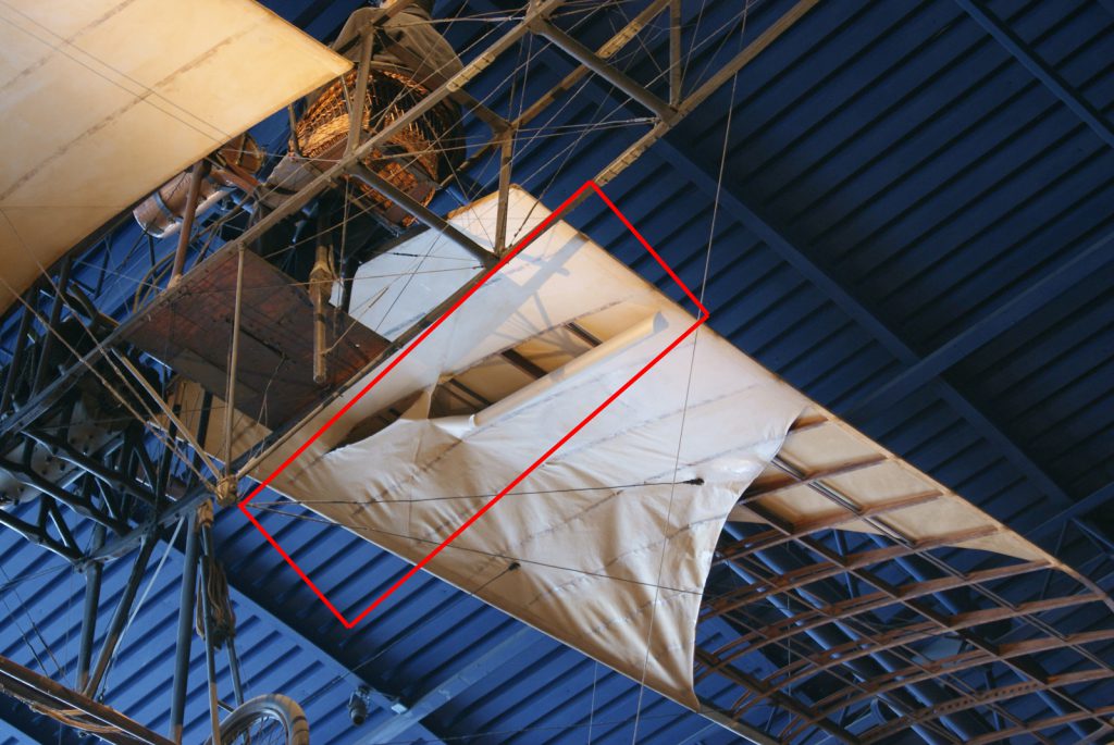 Colour photograph of a large rip in the fabric covering the wing of a JAP Harding Monoplane