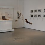 Colour photograph of an exhibition space displaying prosthetic arms hanging by wire