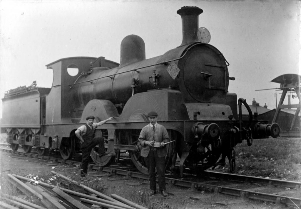Black and white photograph of two railway engineers standing next to a steam train