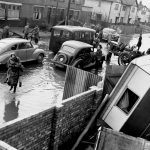 Black and white photograph of a flooded residential street in mid twentieth century