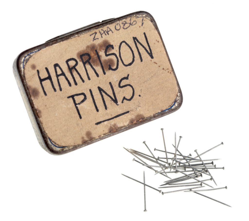 An old liquorice tin labelled with the words Harrison pins and a number of small dressmakers pins