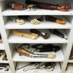 Colour photograph of a number of prosthetic arms in museum storage shelves