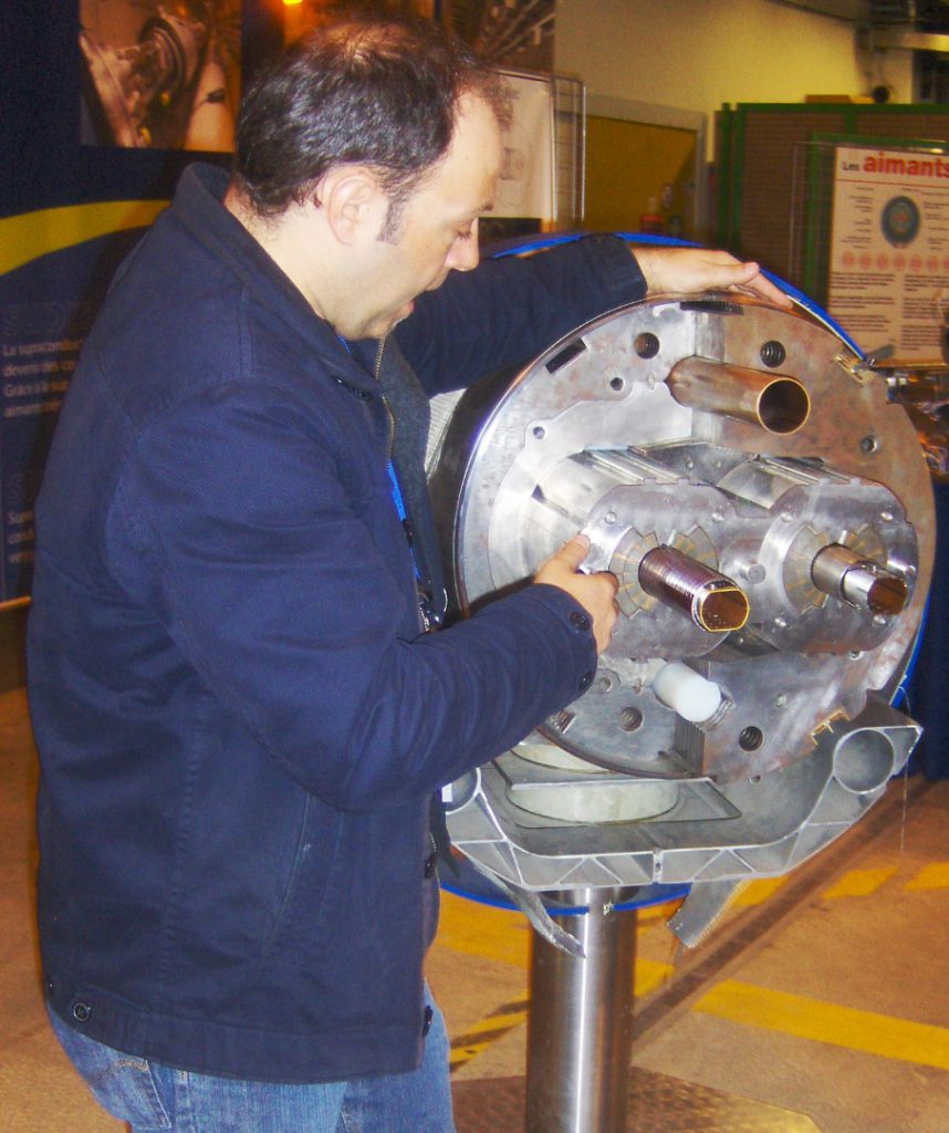 A CERN magnet engineer talks as points out features on a cross section of a circular super-conducting magnet