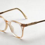 Colour photograph of a pair flesh coloured NHS spectacles