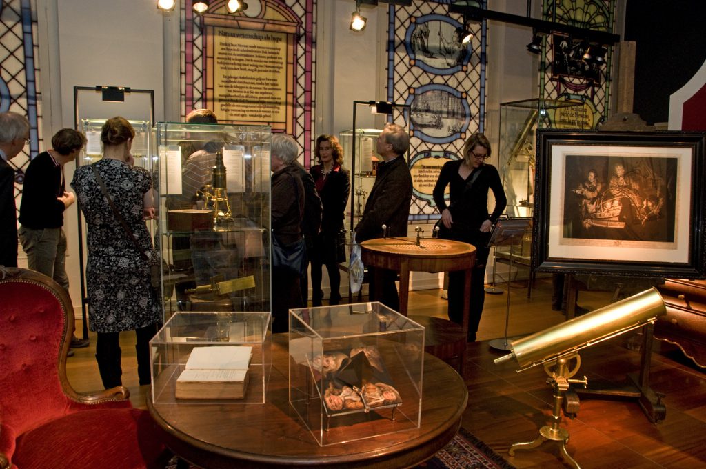 Colour photograph of a group of visitors walking through an exhibition of old scientific instruments