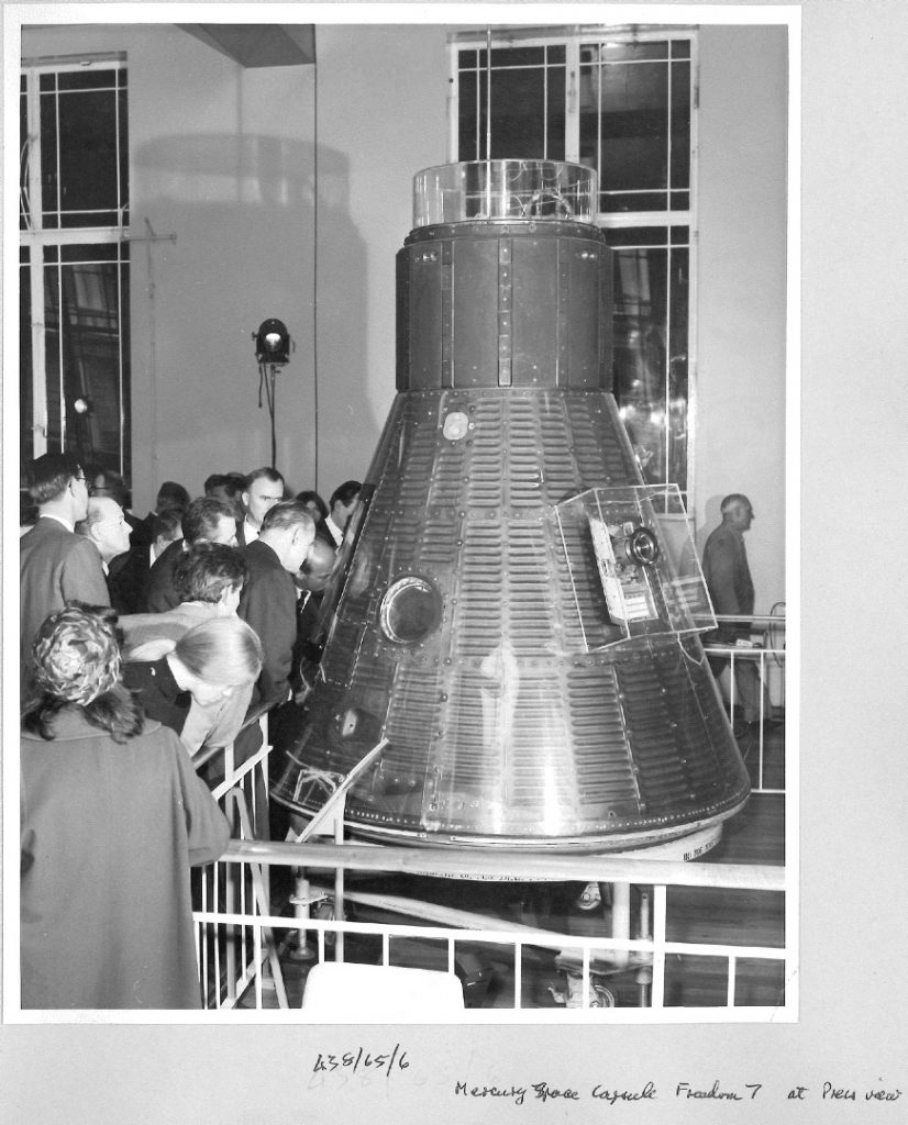 Black and white photograph of a press viewing of the Freedom 7 space capsule