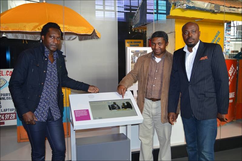 Colour photograph of three particpants from Cameroon in the Information Age gallery