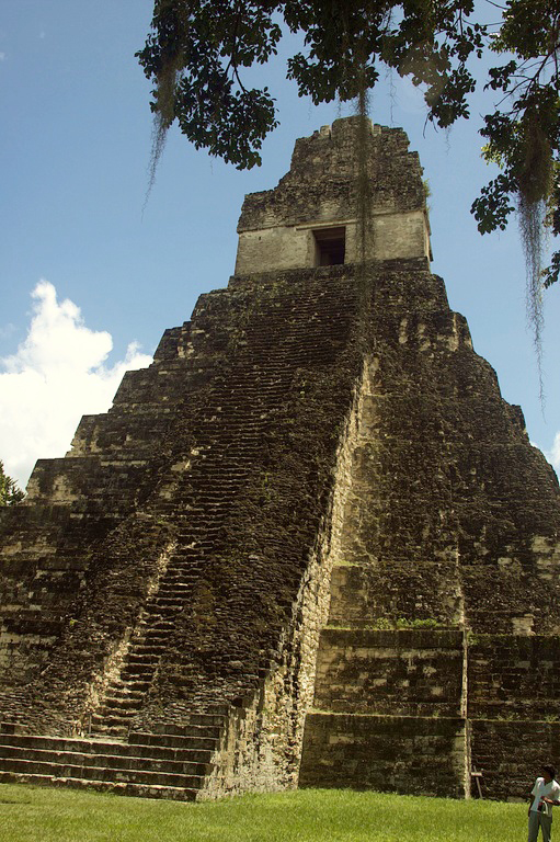 A large, ancient looking pyramidal temple with steps leading up the front to a doorway at the top