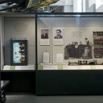 Colour photograph of a display case on computing in the Information Age exhibition showingpictures of early computer specialists a valve from an early computer and a part of the Manchester Mark 1 machine