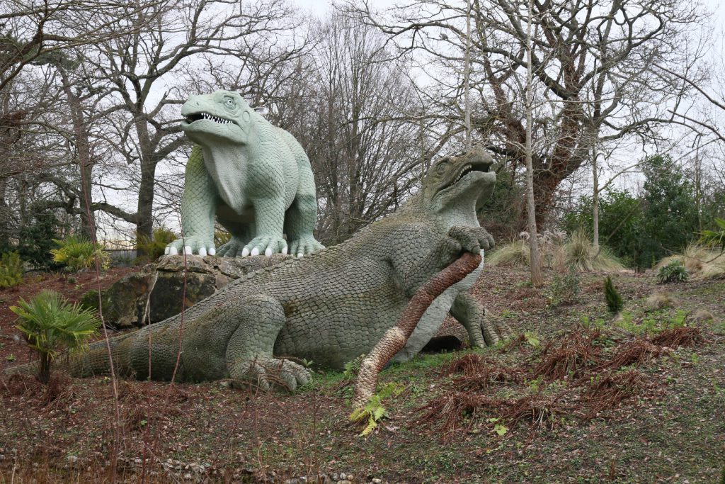 Colour photograph of two concrete Iguanadon models from the nineteenth century in different states of repair