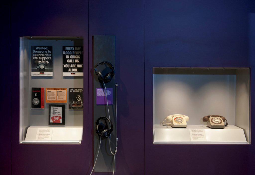 Colour photograph of the empathetic ear display in Information Age showing Samaritans posters and landline telephones