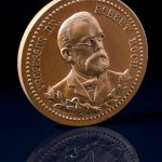 Photograph of a circular bronze medal showing a portrait image of Robert Koch