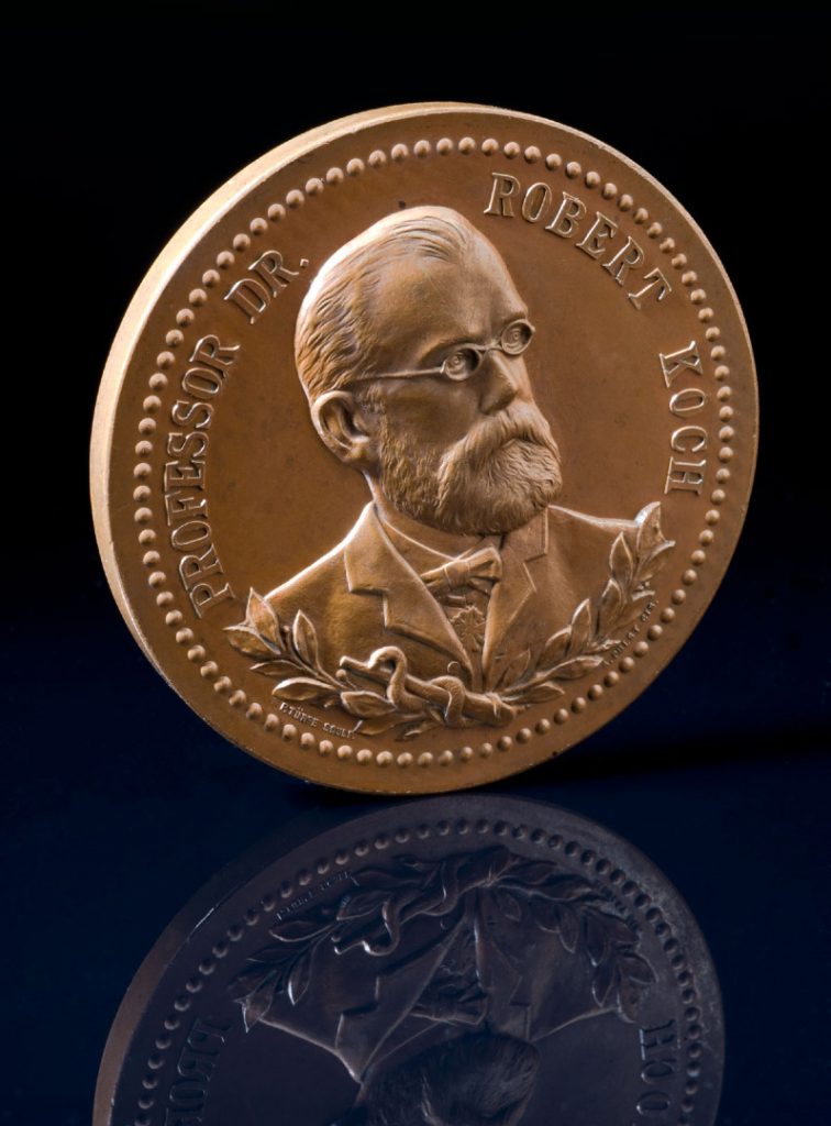 Photograph of a circular bronze medal showing a portrait image of Robert Koch