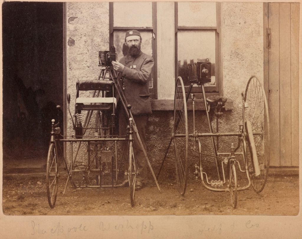 Photographer with two tricycles and two glass plate cameras on tripods from the late nineteenth century