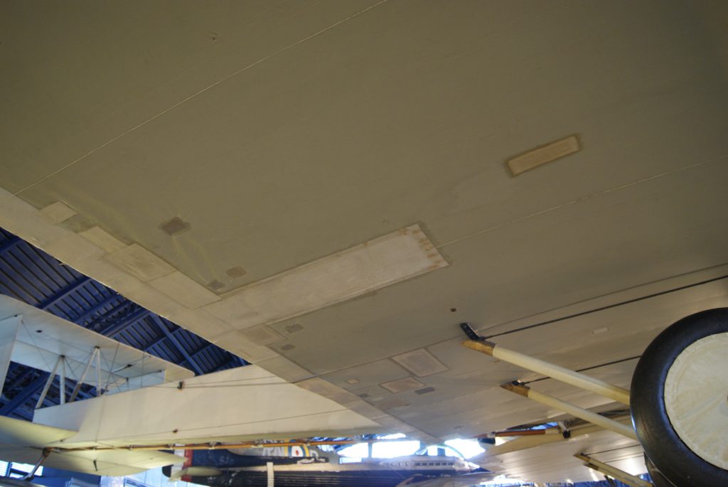 Colour photograph of the underside of the Vickers Vimy aircraft showing numerous patches applied during conservation