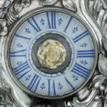 A photograph showing a detail of the clock with a large central citrine quartz jewel