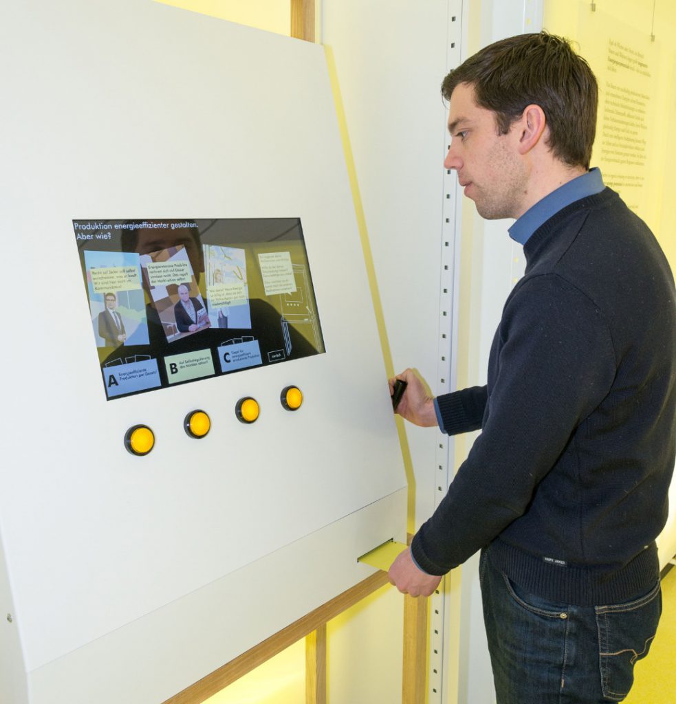 Colour photograph of a museum visitor viewing a digital display