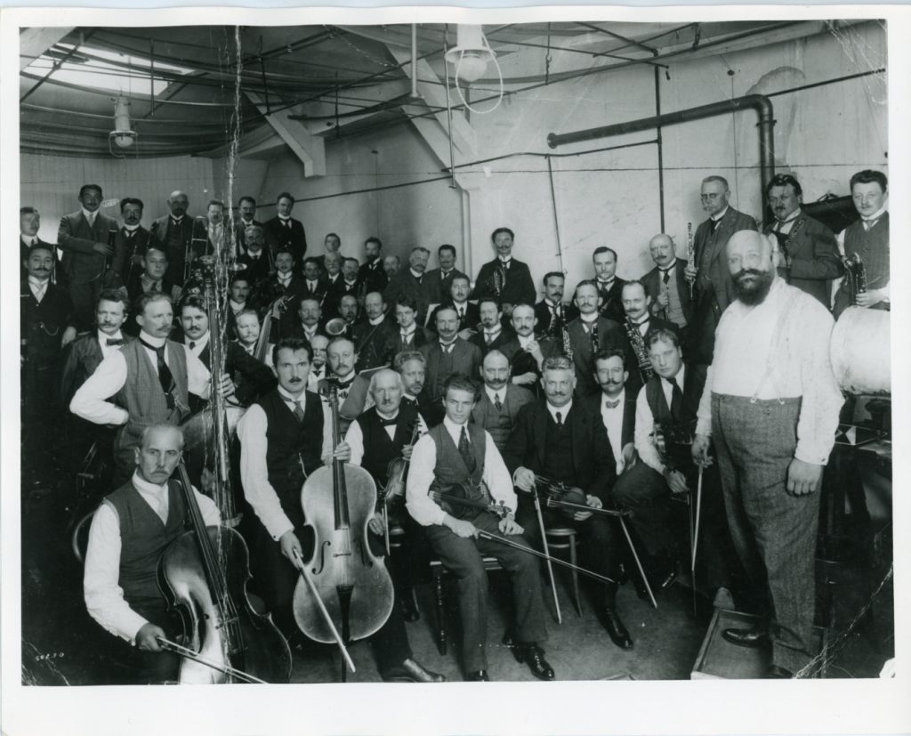 Black and white photograph of the Berlin Philharmonic Orchestra with their instruments in a Gramophone recording studio