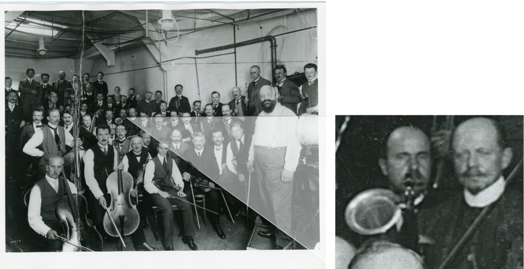 Black and white photograph of the Berlin Philharmonic Orchestra with their instruments in a Gramophone recording studio with a close up of the horn of a stroh violin
