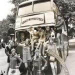 Black and white publicity photograph of a double decker bus with Flying Scotsman printed on the front and a number of young women surrounding the bus