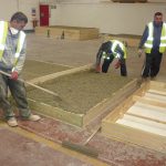 Colour photograph of workers precasting hempcrete panels for use in the storage building
