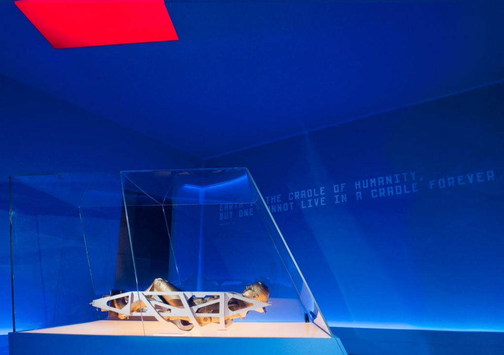 Colour photograph of a section of the Cosmonauts exhibition showing a mannequin lying inside a spacecraft seat