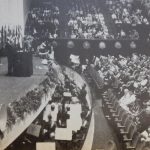 Black and white photograph from the World Power Conference of a large stage with seated presenters and a large seated audience
