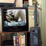 Colour photograph showing a television with an image of a woman receiving an examination during birth