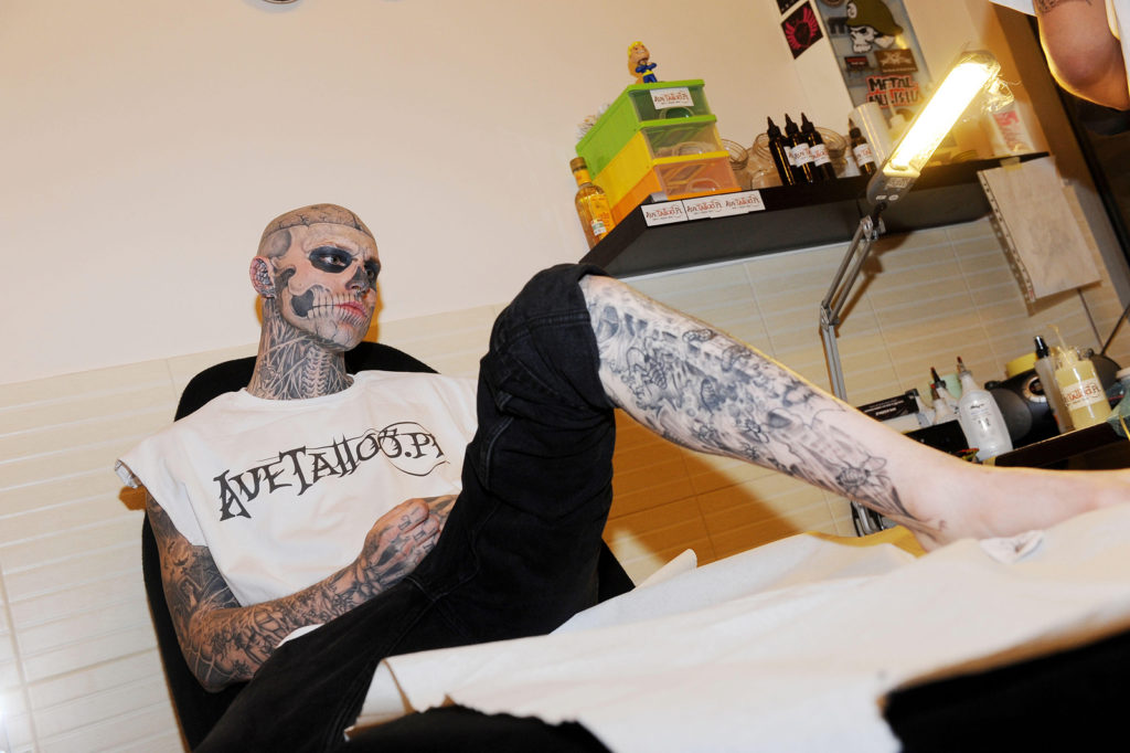 Colour photograph of a heavily tattooed man at a tattoo parlour