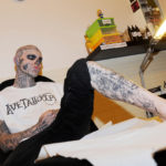 Colour photograph of a heavily tattooed man at a tattoo parlour
