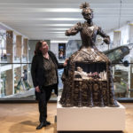 Colour photograph of the Santa Medicina sculpture situated on gallery with artist Eleanor Crook