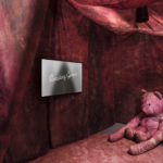 Colour photograph of a video showing in an exhibition room with a large pink teddy bear